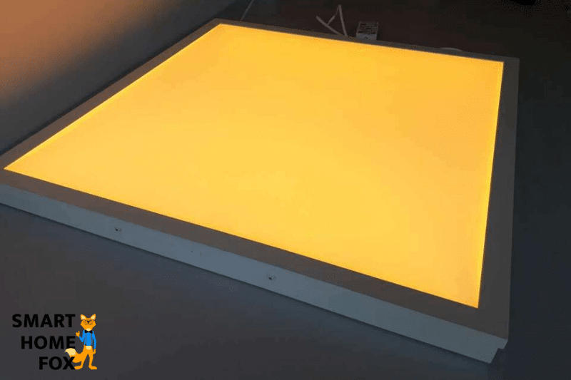 Ein quadratischer Float Paneel von IKEA liegt auf dem Tisch und leuchtet gelb